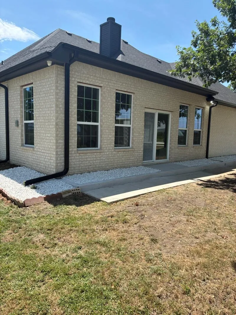 Instalación de Concreto y Grava — Extensión de pasarela con grava decorativa y borde de ladrillo rojo